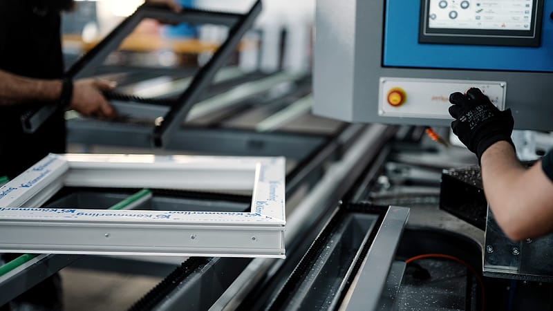 A workbench in a small factory with metal components in a tray and a partly assembled unit under a task light.