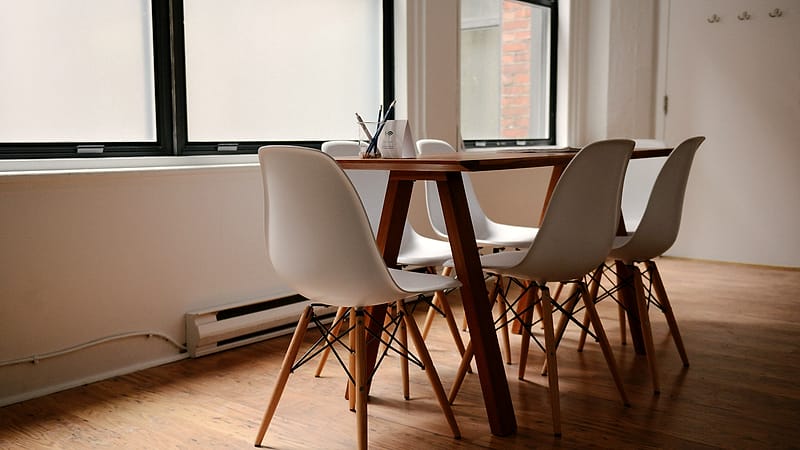 Three stacks of paper of different heights on a desk beside a pen, a stapler and a half-filled coffee cup.