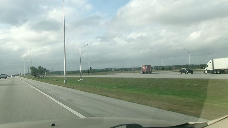 A weigh station scale house beside an inspection bay with lane markings and an overhead gantry of cameras.