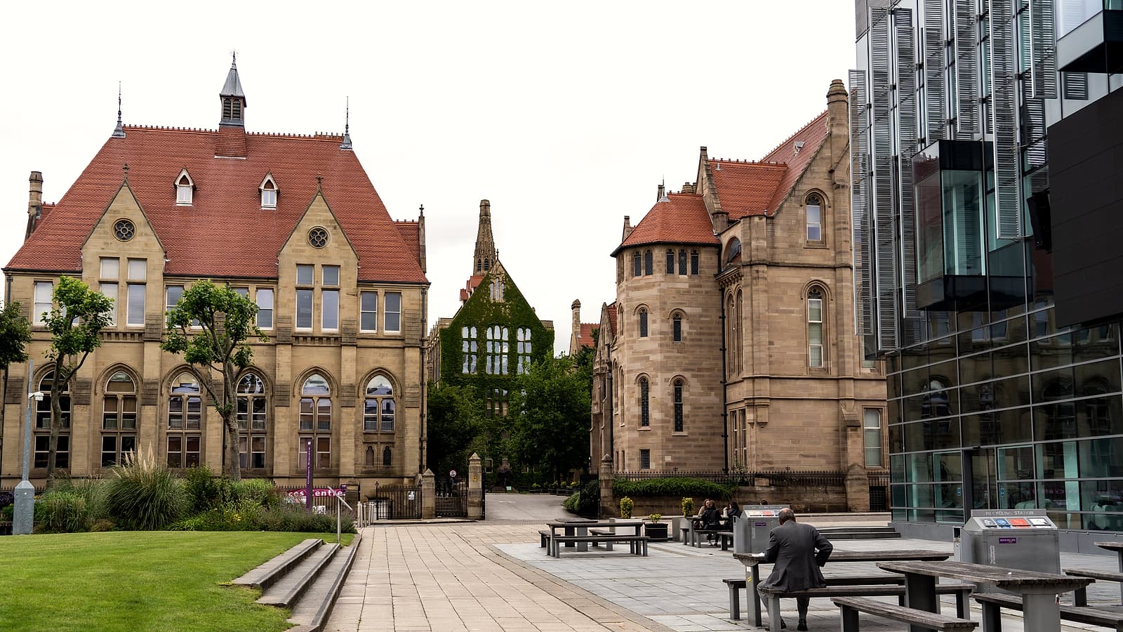 A brick campus building with tall arched windows and a paved walkway leading toward its main entrance.