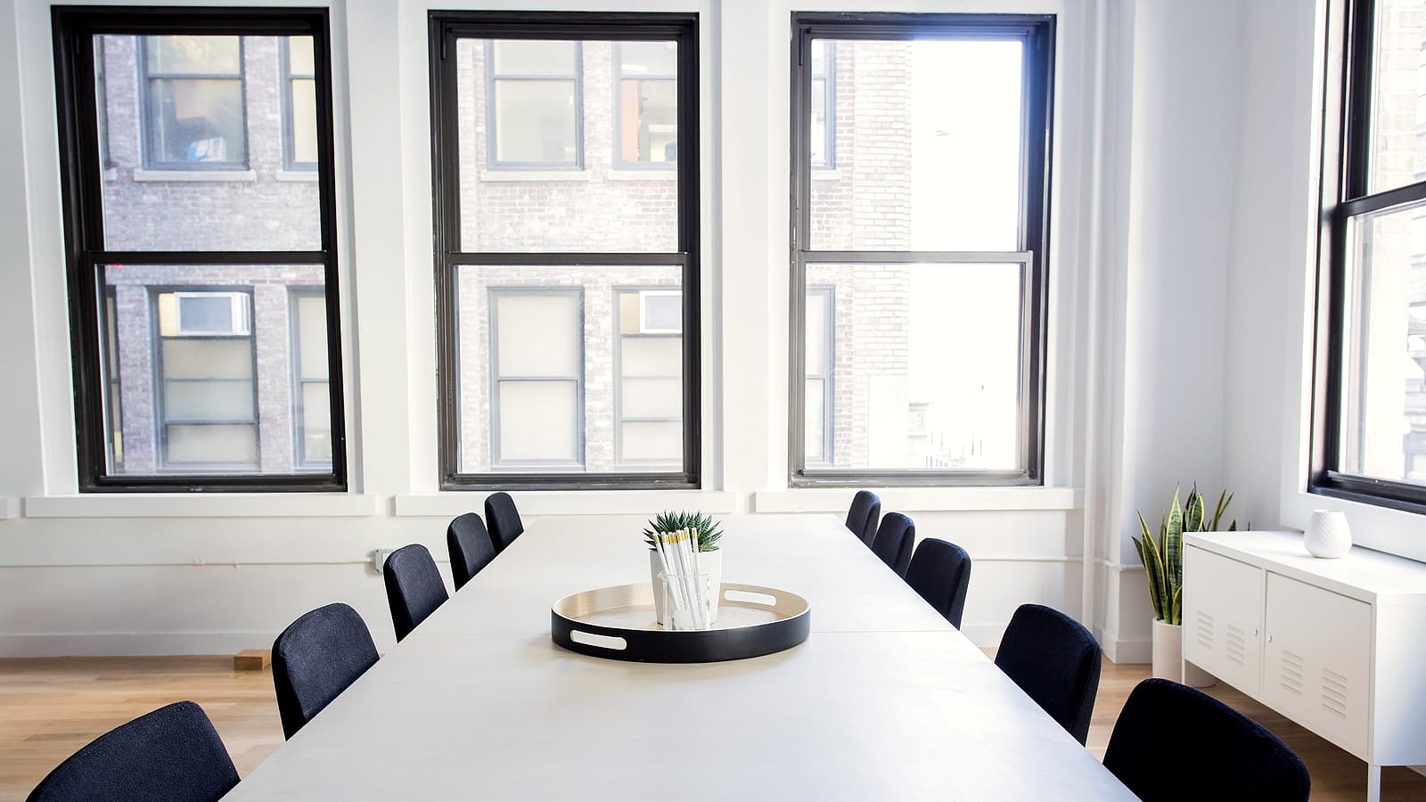 Two chairs facing each other across a narrow table in a bare meeting room with a closed door behind.