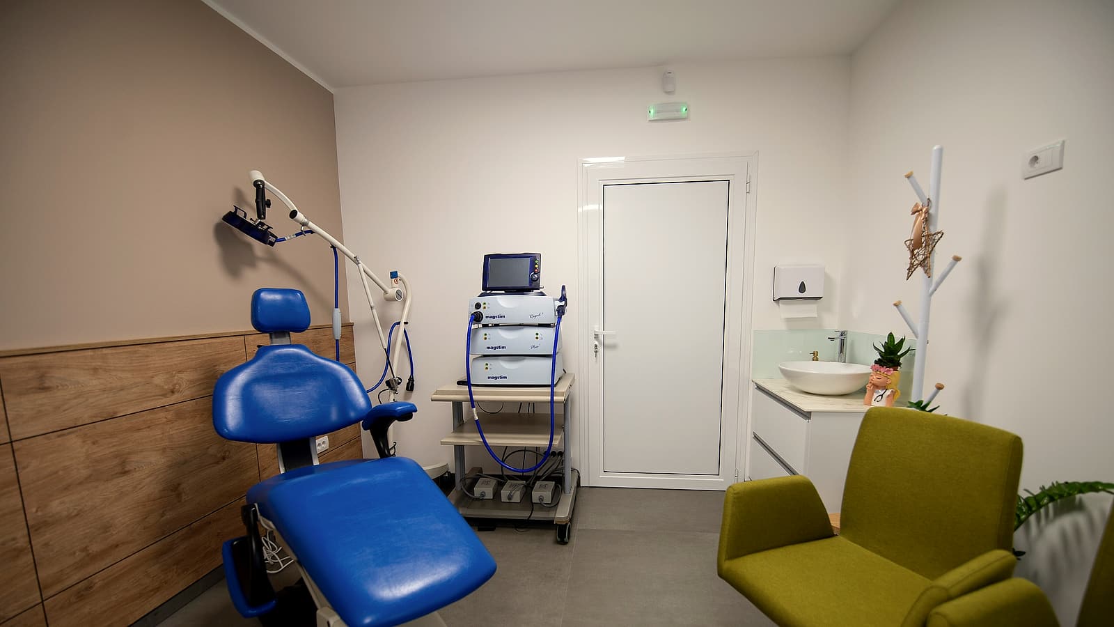 A short hospital corridor where two signposted passages branch from a single doorway under even ceiling light.